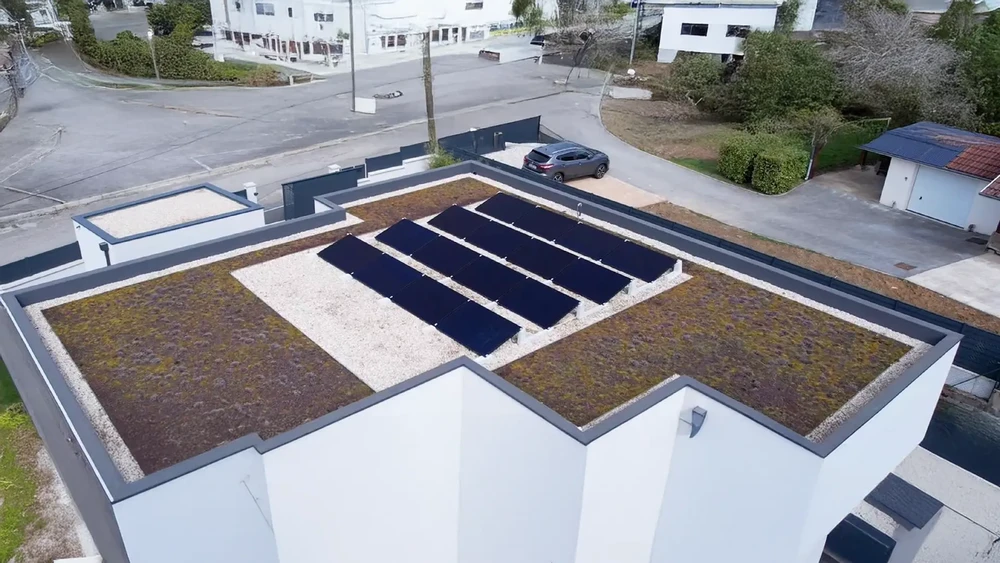 Vue aérienne d'un bâtiment moderne avec toiture-terrasse végétalisée équipée de panneaux solaires photovoltaïques