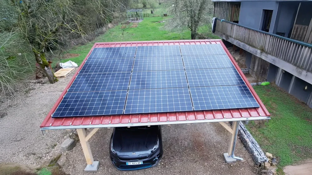 Carport extérieur avec structure métallique abritant une voiture électrique Kia noire