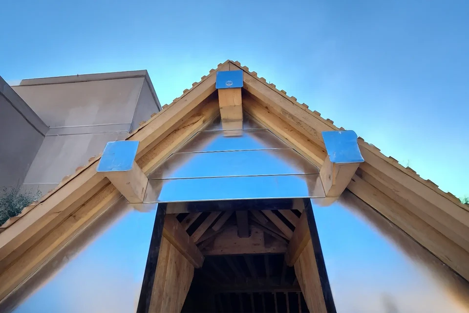 Chantier de construction résidentielle en extérieur, toiture en tuiles métalliques grises ondulées avec gouttière aluminium installée