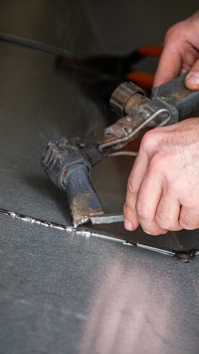 Atelier d'artisan avec ceinture à outils en cuir marron contenant divers outils de construction et menuiserie disposés sur planches de bois clair