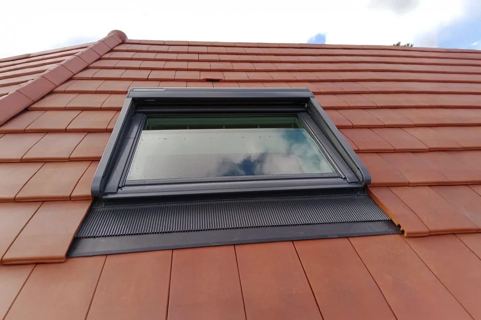 Extérieur d'une maison avec toiture en tuiles terre cuite oranges sous ciel bleu